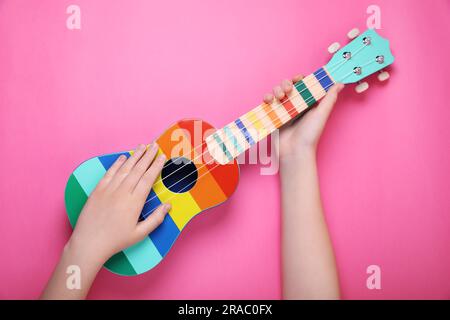 Cute girl hugs ukulele with her eyes closed and smiles, isolated