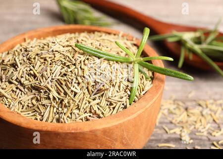 Dry and fresh rosemary in wooden bowl on table, closeup Stock Photo