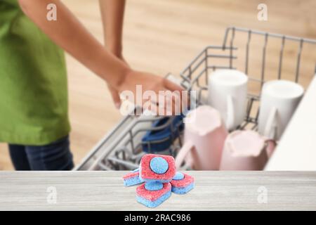 Dishwasher detergent tablets on wooden table in kitchen, selective focus Stock Photo