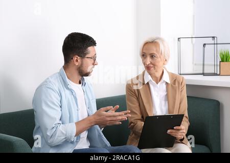 Woman having conversation with man on sofa in office. Manager conducting job interview with applicant Stock Photo