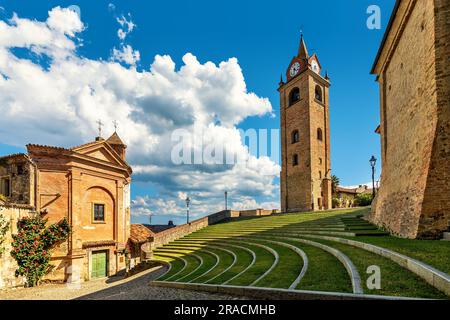 Small church, belfry and open air amphitheater under blue sky with white clouds in small town of Monforte d'Alba, Italy. Stock Photo