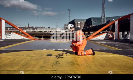 Marine engineer sounding fuel oil cargo tank on cargo deck on supply vessel in harbor. Stock Photo