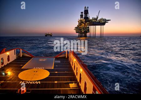 Supply vessel going for cargo operations with jack-up rig. Stock Photo
