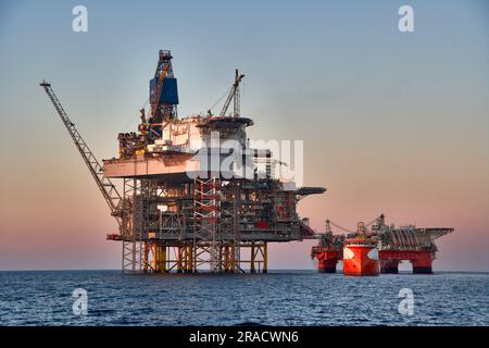 Drilling rig crude oil production in the sea.Jack up oil rig and semi submersible platform, during cargo operations with supply vessel. Stock Photo