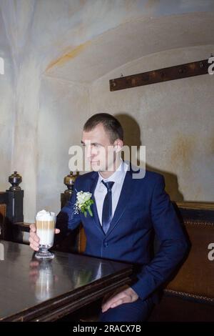 Groom's hands holding cup of coffee. Handsome man drinking coffee at in cafe Stock Photo