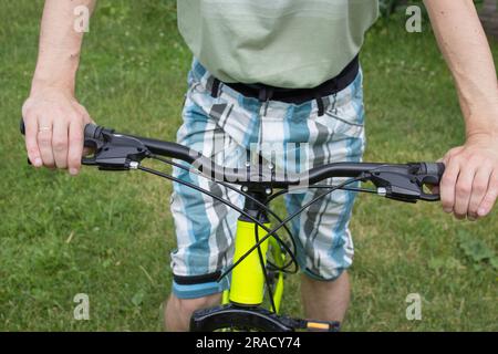 The guy in shorts sits on a bike in the front view and holds the wheel Stock Photo
