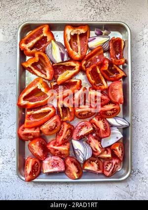 Tomatoes, peppers and red onions on an oven tray Stock Photo