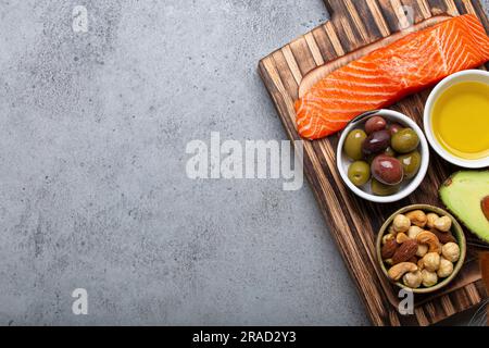 Food sources of healthy unsaturated fat and omega 3: fresh salmon fillet, avocado, olives and nuts Stock Photo