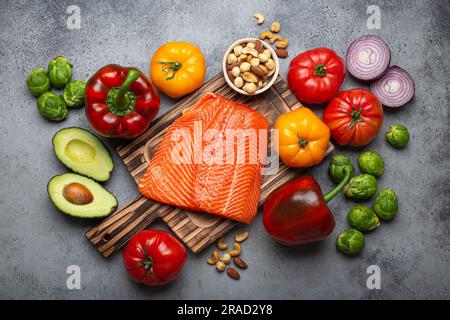Fresh salmon fillet on wooden cutting board, organic vegetables and nuts Stock Photo