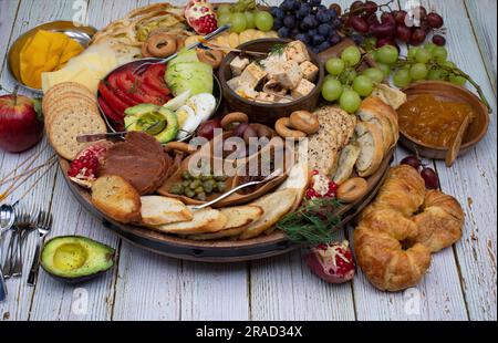Appetizer board with crackers, cheese, vegetables, and grapes Stock Photo