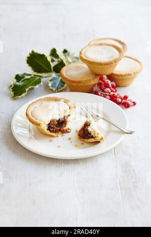 Mince pie christmas cakes with holly and bauble decorations over red ...