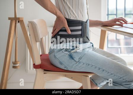 Man wearing back support belt on lower back during exacerbation to treatment of hernia. Stock Photo