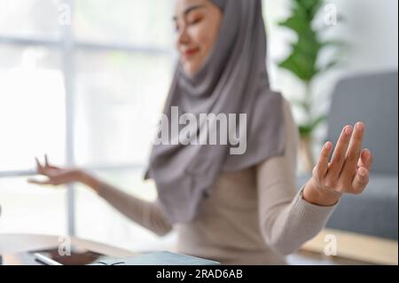 Muslim Woman In Headscarf Meditating With Closed Eyes, Making Mudra Gesture With Fingers. close-up image Stock Photo