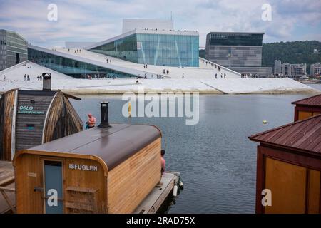 Oslo, Norway, June 20, 2023: Adults enjoy the floating sauna rafts  of Oslo Fjord Sauna, on the fjord, between the Opera house and Sørenga wharf. Stock Photo