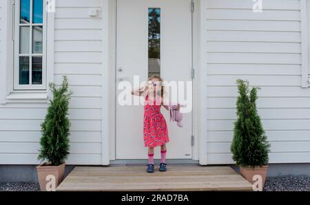 portrait of a young girl posing outside her front dog with a soft toy Stock Photo