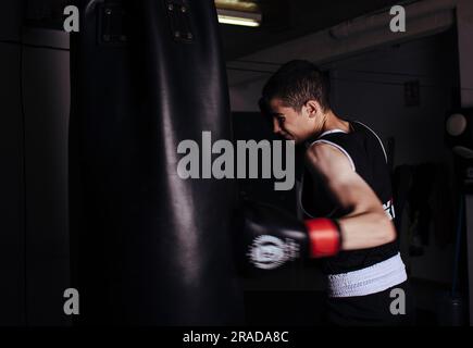 Young man boxer practicing a hit boxing during workout. Stock Photo