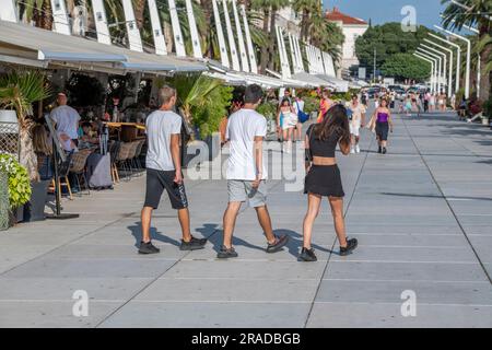 group of teenagers walking through the old town of grad split in croatia. young people on holiday together on the waterfront at split, croatia. Stock Photo