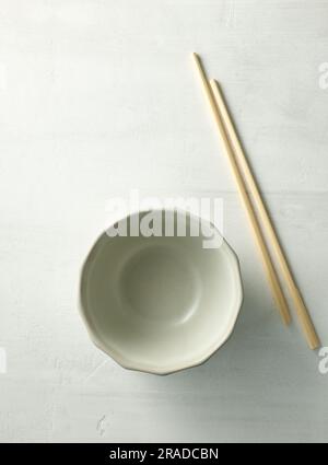 empty bowl and chopsticks on light kitchen table, top view Stock Photo