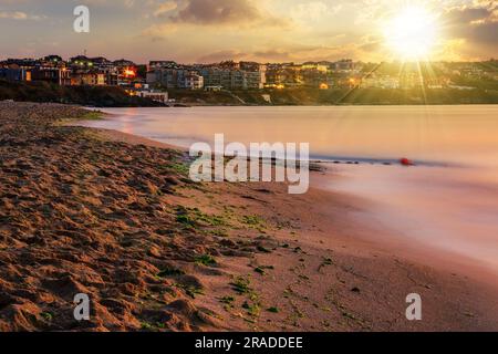 urban sand beach in the early morning calm at sunset. resort town wakes up after rough night in evening light Stock Photo