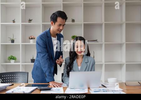 Business man having a discussion with his colleague in an office. Two business people using a laptop in a meeting. Teamwork and collaboration between Stock Photo