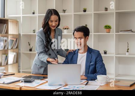 Business man having a discussion with his colleague in an office. Two business people using a laptop in a meeting. Teamwork and collaboration between Stock Photo