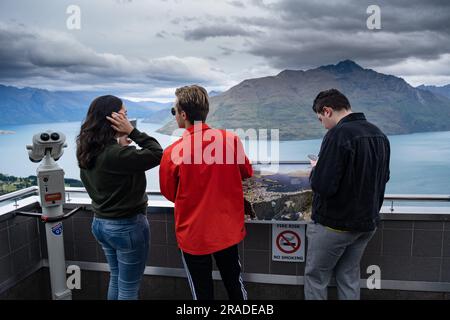 Tourists take mobile phone pictures at the Skyline Resort on Bob's Peak above Queenstown and Lake Wakatipu in New Zealand. Photo: Rob Watkins Stock Photo