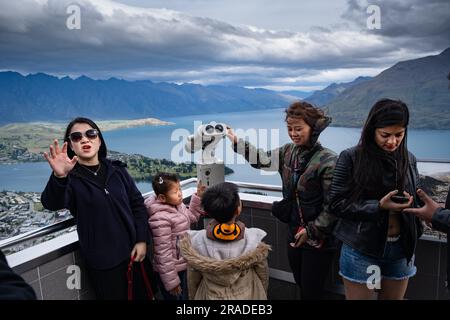 Asian tourists take mobile phone pictures at the Skyline Resort on Bob's Peak above Queenstown and Lake Wakatipu in New Zealand. Photo: Rob Watkins Stock Photo
