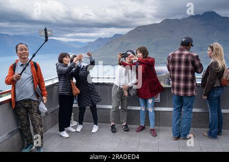 Asian tourists take mobile phone pictures at the Skyline Resort on Bob's Peak above Queenstown and Lake Wakatipu in New Zealand. Photo: Rob Watkins Stock Photo