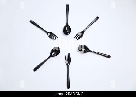 Top view composition of black plastic forks and spoons placed on white background Stock Photo