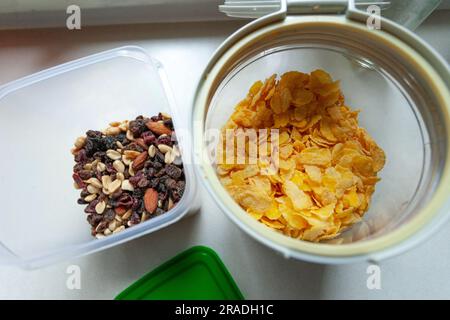 Delicacies and cornflakes in plastic containers standing on the kitchen counter, top view Stock Photo