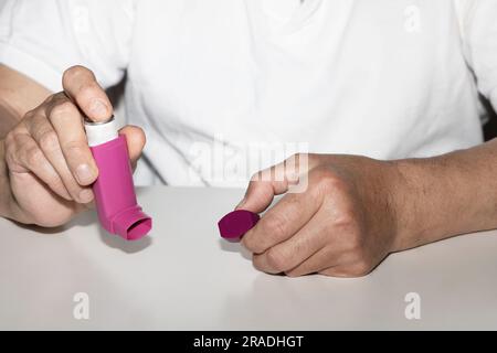 Man holding asthma inhaler in his hands. Asthma medications inhalers on a white background. Lung disease. Stock Photo