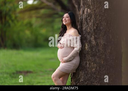 young beautiful pregnant woman stroking her belly in the park Stock Photo