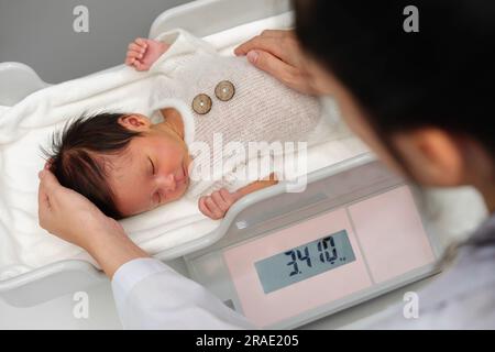 https://l450v.alamy.com/450v/2rae205/newborn-baby-weight-measurement-on-the-digital-scales-with-doctor-in-hospital-2rae205.jpg