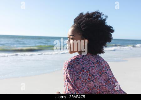 Happy african american woman smiling on sunny beach by the sea Stock Photo