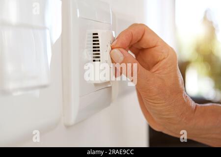 Female hand adjusting thermostat to turn on the radiator heater at home ...