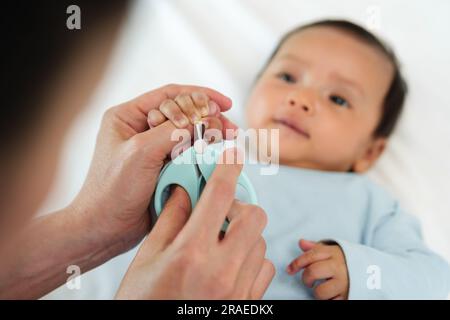 mother cutting newborn baby's hand fingernails with nail scissors. Stock Photo