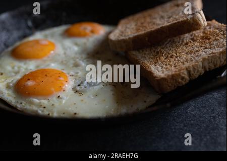 Fried eggs with toast in a cast iron pan Stock Photo