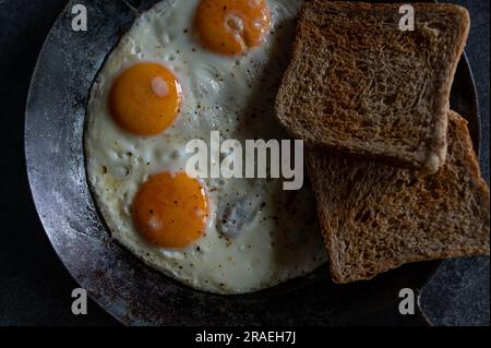 Fried eggs with toast in a cast iron pan Stock Photo