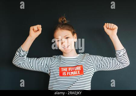 Studio shot of young strong preteen girl flexing arms muscles Stock Photo