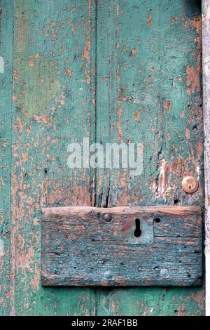 Weathered wooden door, with distressed paint work, over painted, preserved wood grain and rustic texture, with newly fitted barrel lock, Amalfi, Italy. Stock Photo