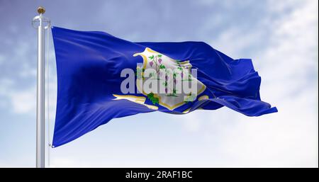 The Connecticut state flag waving on a clear day. White shield on blue background featuring three grapevines each bearing bunches of grapes. Textured Stock Photo