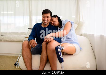 Couple of man and woman using laptop and relaxing at home, Positive woman with prosthetic leg having fun on weekend at home, Leisure lifestyles and Stock Photo