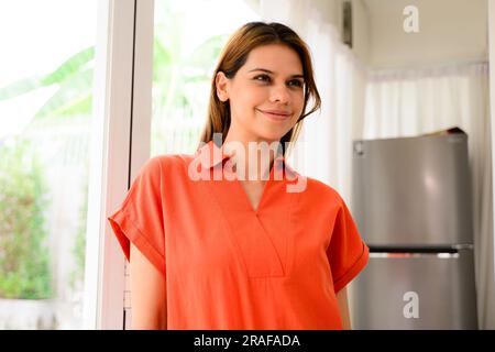 Smiling portrait of positive woman relaxing at home on weekend, Happy lady in bright clothes posing at home indoor, Healthy single woman standing in Stock Photo
