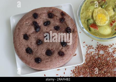 Navara rice vattayappam. Steamed rice cake made with a fermented batter of navara rice and coconut and steamed in a round dish served with kerala egg Stock Photo