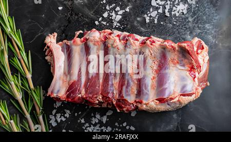 Raw rack of lamb with parsley and oil. On a black background. High quality photo Stock Photo