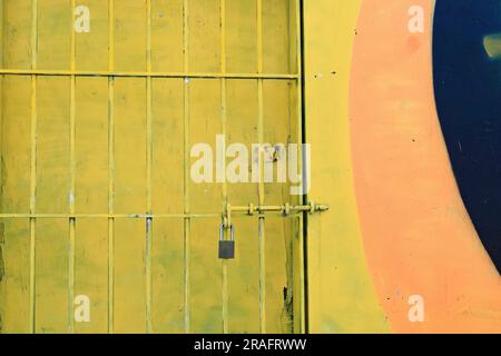 724 Security grill for chipped yellow wooden door on colorist wall along Queen Elizabeth Drive, Bondi Beach. Sydney-Australia. Stock Photo