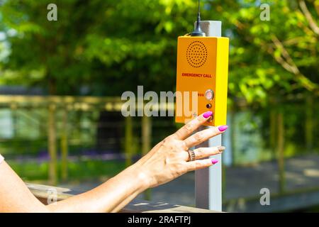 woman calling rescuers by walkie-talkie in the park. park help signal. finger presses the SOS button Stock Photo