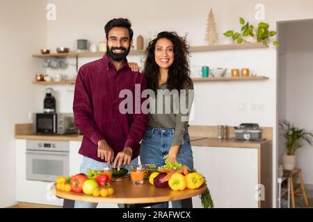 Happy middle eastern husband and wife cooking lunch in kitchen interior, looking at camera and smiling, copy space Stock Photo