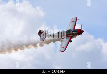 Vintage Yakovlev  Yak - 52 aircraft in flight with smoke trail. Stock Photo