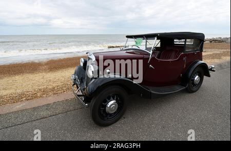 Vintage Red Morris 8 motor Car parked on seafront promenade beach and sea in background. Stock Photo